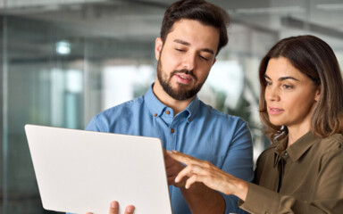 Zwei Businesspartner suchen ein kostenloses Girokonto auf dem Laptop.