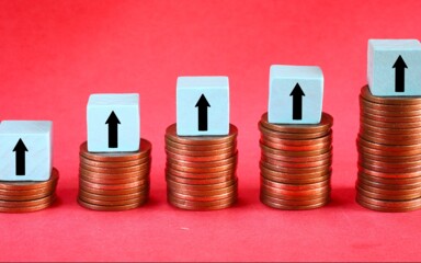 Symbolbild: Münzstapel mit Pfeilen nach oben stehen für steigende Zinsen und höhere Erträge bei Sparanlagen wie Tagesgeld.