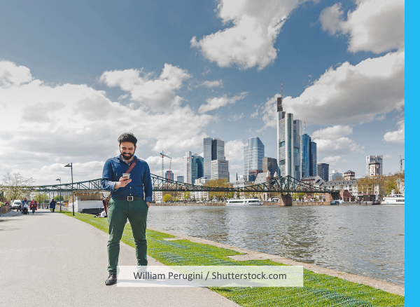 Ein Mann schaut auf sein Handy, im Hintergrund die Frankfurter Skyline