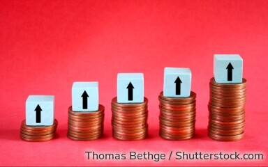 Symbolbild: Münzstapel mit Pfeilen nach oben stehen für steigende Zinsen und höhere Erträge bei Sparanlagen wie Tagesgeld.