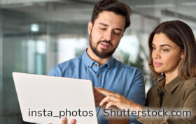Zwei Businesspartner suchen ein kostenloses Girokonto auf dem Laptop.