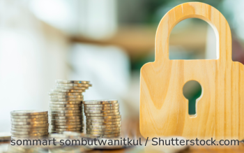 Ein Münzstapel, daneben ein Schloss aus Holz