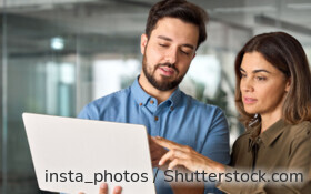 Zwei Businesspartner suchen ein kostenloses Girokonto auf dem Laptop.
