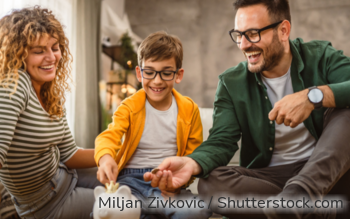 Eine dreiköpfige Familie wirft Münzen in ein Sparschwein