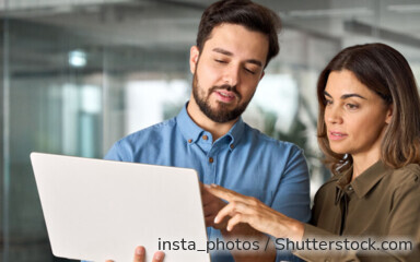 Zwei Businesspartner suchen ein kostenloses Girokonto auf dem Laptop.