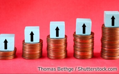 Symbolbild: Münzstapel mit Pfeilen nach oben stehen für steigende Zinsen und höhere Erträge bei Sparanlagen wie Tagesgeld.