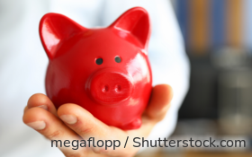 Ein Mann mit Krawatte hält ein rotes Sparschwein in der ausgestreckten Hand