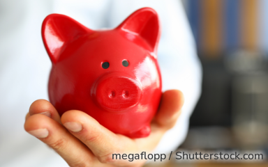 Ein Mann mit Krawatte hält ein rotes Sparschwein in der ausgestreckten Hand